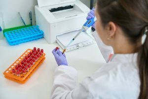 Woman laboratory assistant works with blood samples loaded into test tubes